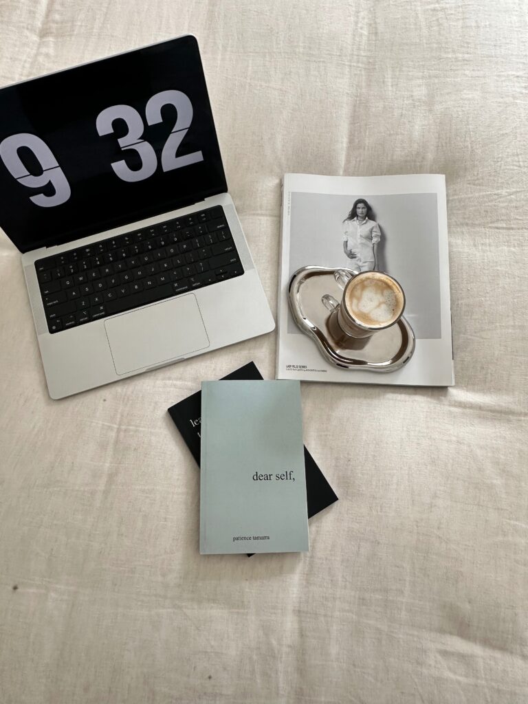 Keyword Mapping | High Tide Strategy Full Service Marketing Agency | Laptop with a 9:32 clock screensaver, a magazine, cappuccino on a silver tray, and a blue book titled "dear self," on a beige cloth. Cozy, serene mood.