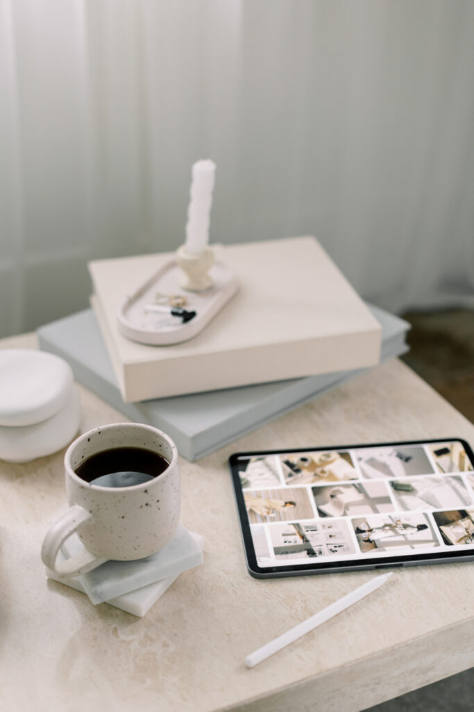 SEO Tips for Photographers | High Tide Strategy Full Service Marketing Agency | A cozy workspace with a mug of coffee, a tablet displaying a photo gallery, a stylus, stacked books, and a candle, creating a calm, creative ambiance.