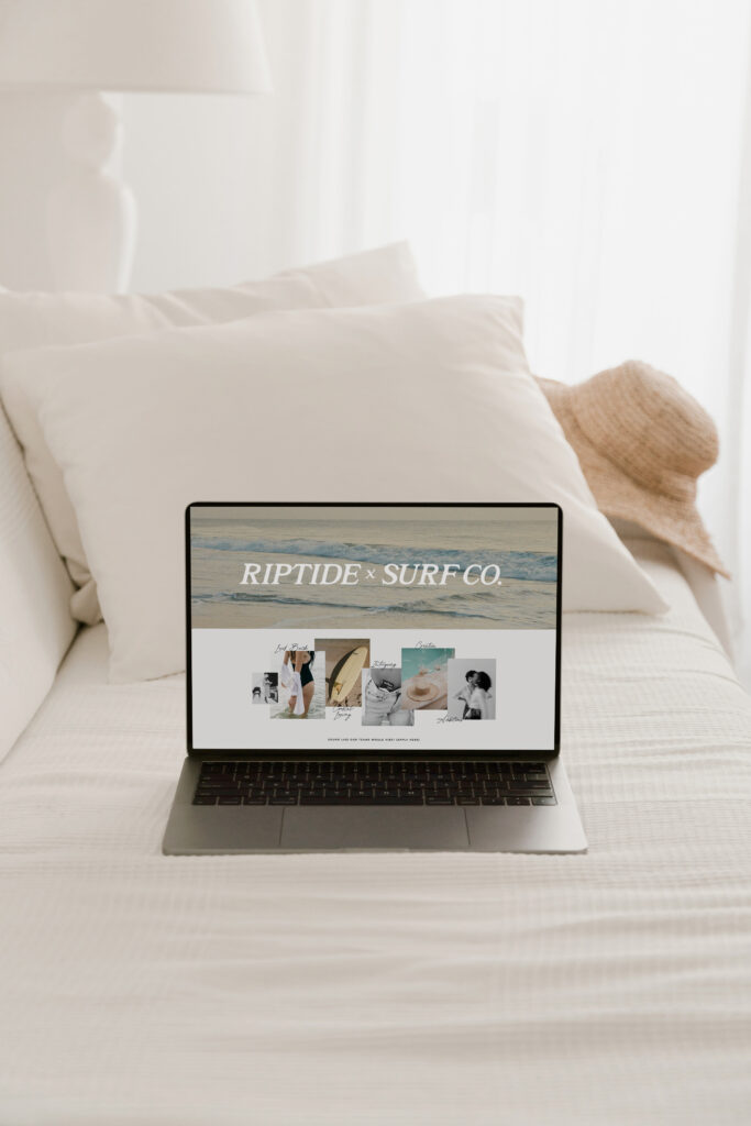 Showit Website Designer | High Tide Strategy Full Service Marketing Agency | Laptop on a bed with white sheets displays a website reading "Riptide x Surf Co" alongside beach-themed images. A straw hat rests nearby.