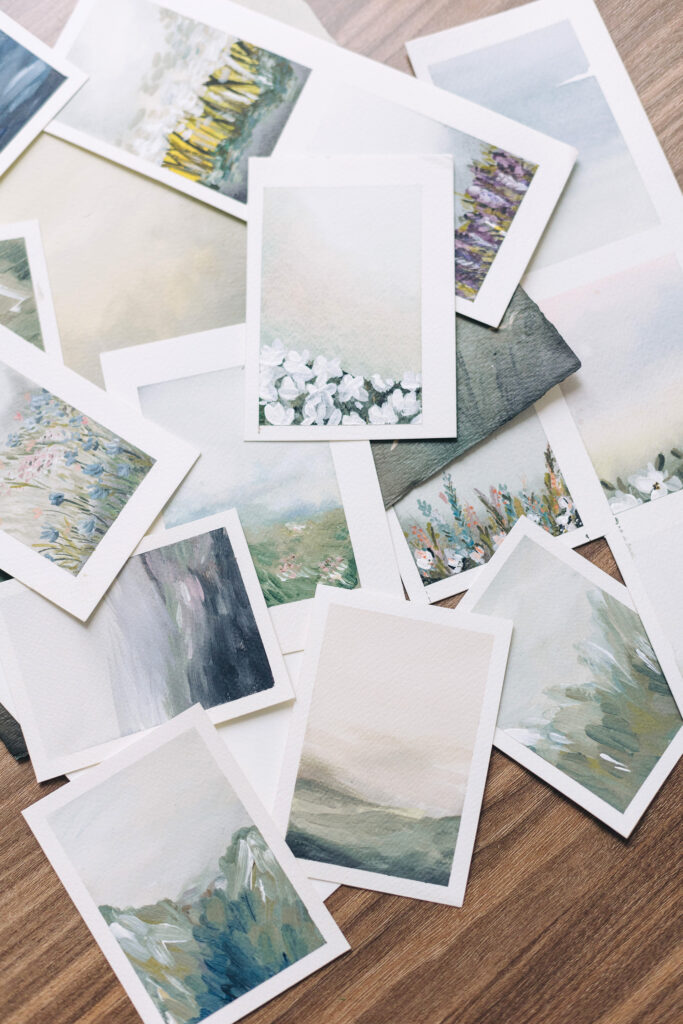 SEO Services for Photographers | High Tide Strategy Full Service Marketing Agency | A collection of small watercolor paintings on a wooden surface, featuring serene landscapes with soft, muted colors, evoking a calm and peaceful tone.