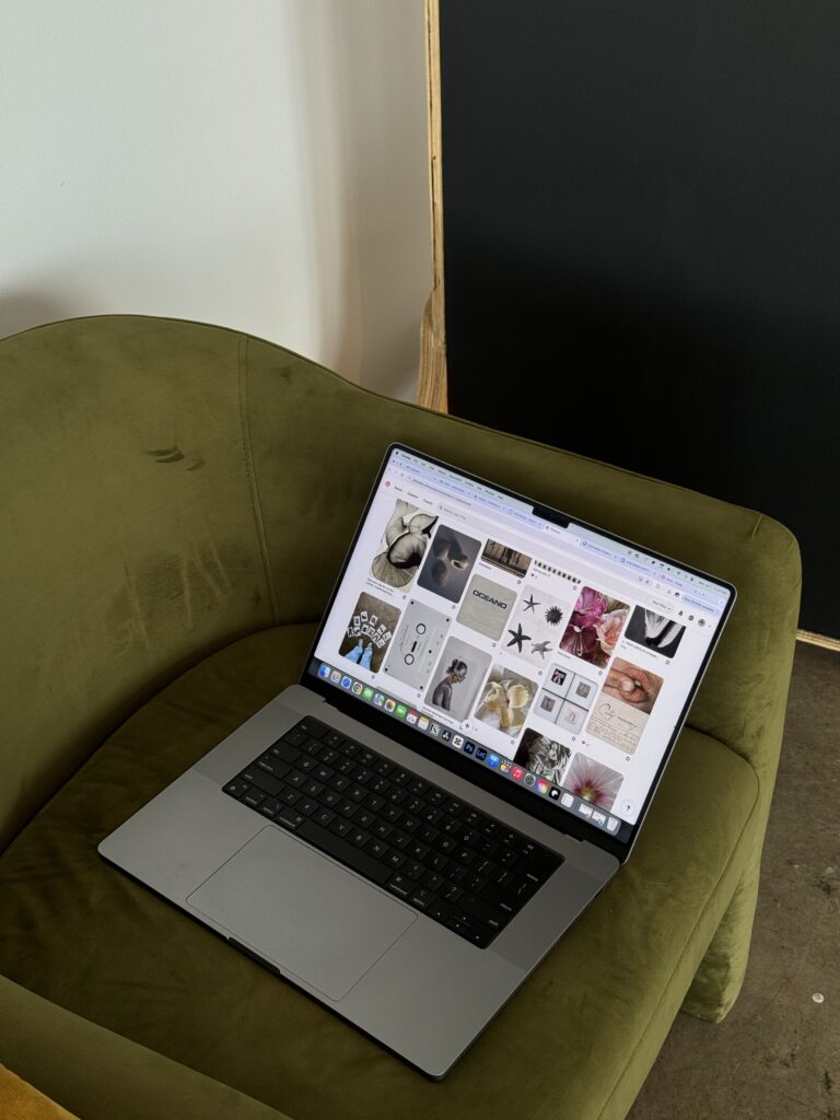 Social Media Marketing for Creative Entrepreneurs | High Tide Strategy Full Service Marketing Agency | Laptop displaying a Pinterest-like webpage with various images, resting on a green velvet chair. The setting feels cozy and creative.