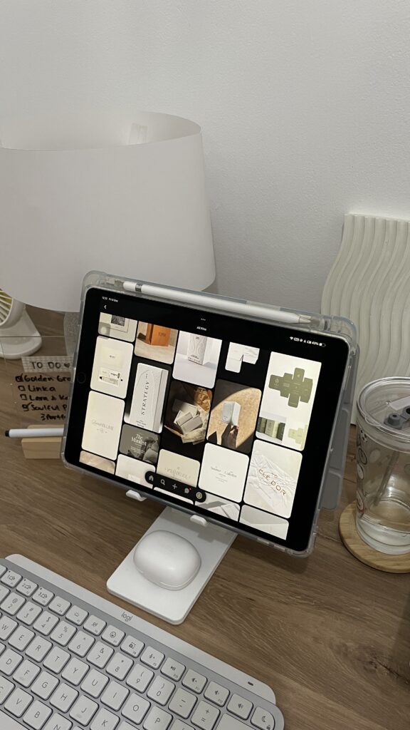 Marketing Plan for Interior Design Business | High Tide Strategy Full Service Marketing Agency | A tablet on a stand displays various design images. It's on a wooden desk with a keyboard, lamp, glass, and a handwritten to-do list nearby, evoking a creative workspace.