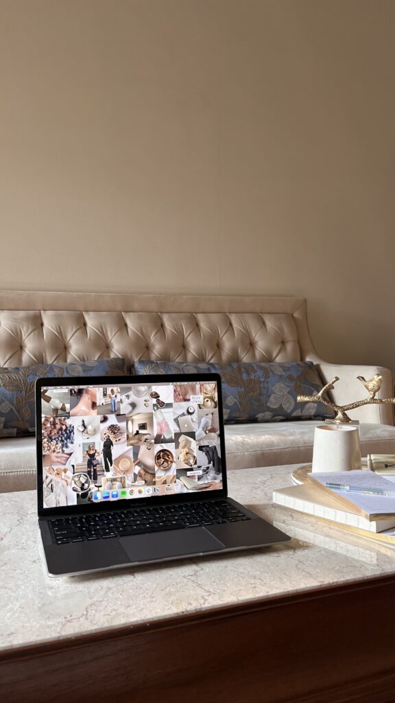 Boutique Marketing Ideas | High Tide Strategy Full Service Marketing Agency | A laptop showing a collage of images on its screen sits on a marble table in front of a beige tufted sofa. The ambiance is cozy and minimalist.