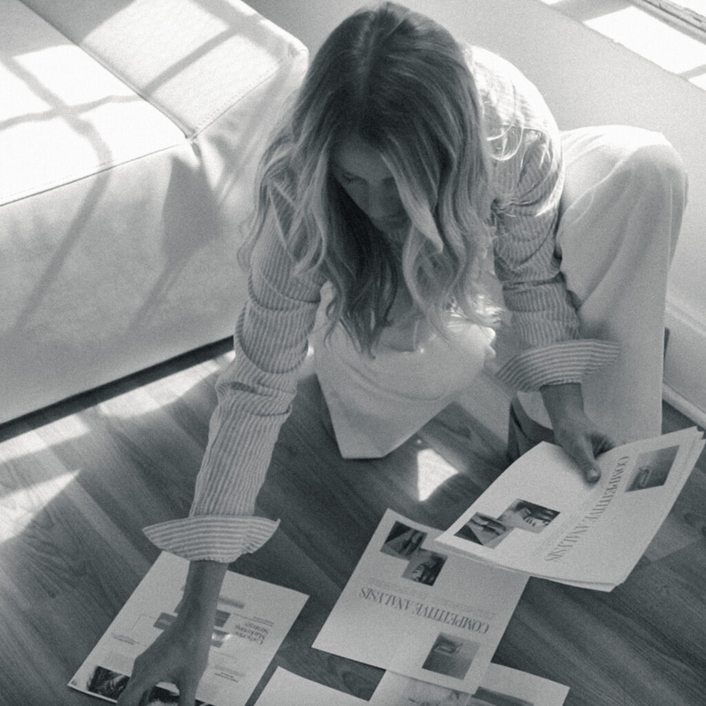 Mandy reviewing printed website layouts and creative materials on the floor while developing SEO strategies for photographers.