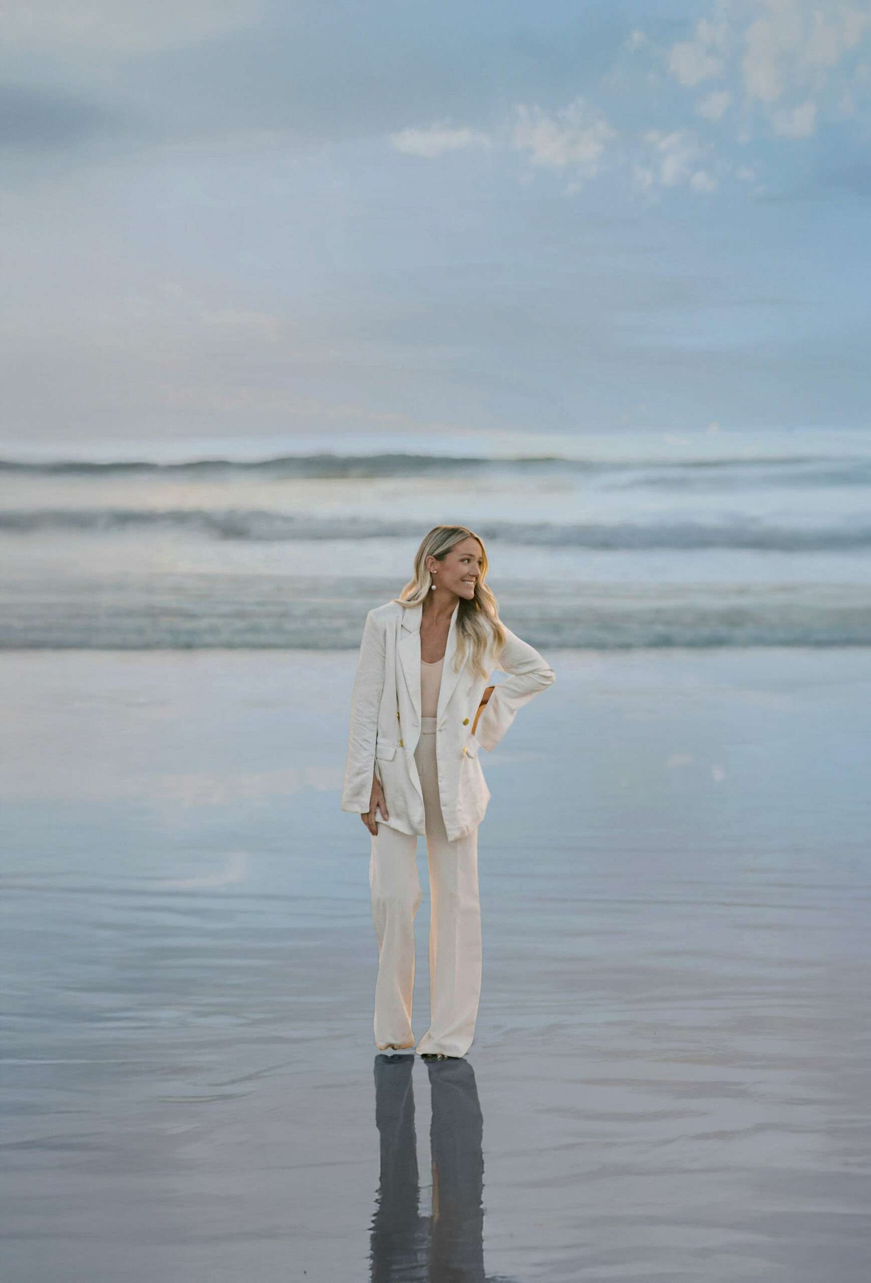 Mandy Ford Headshot standing on the beach in a white suite | SEO expert for photographers and wedding pros