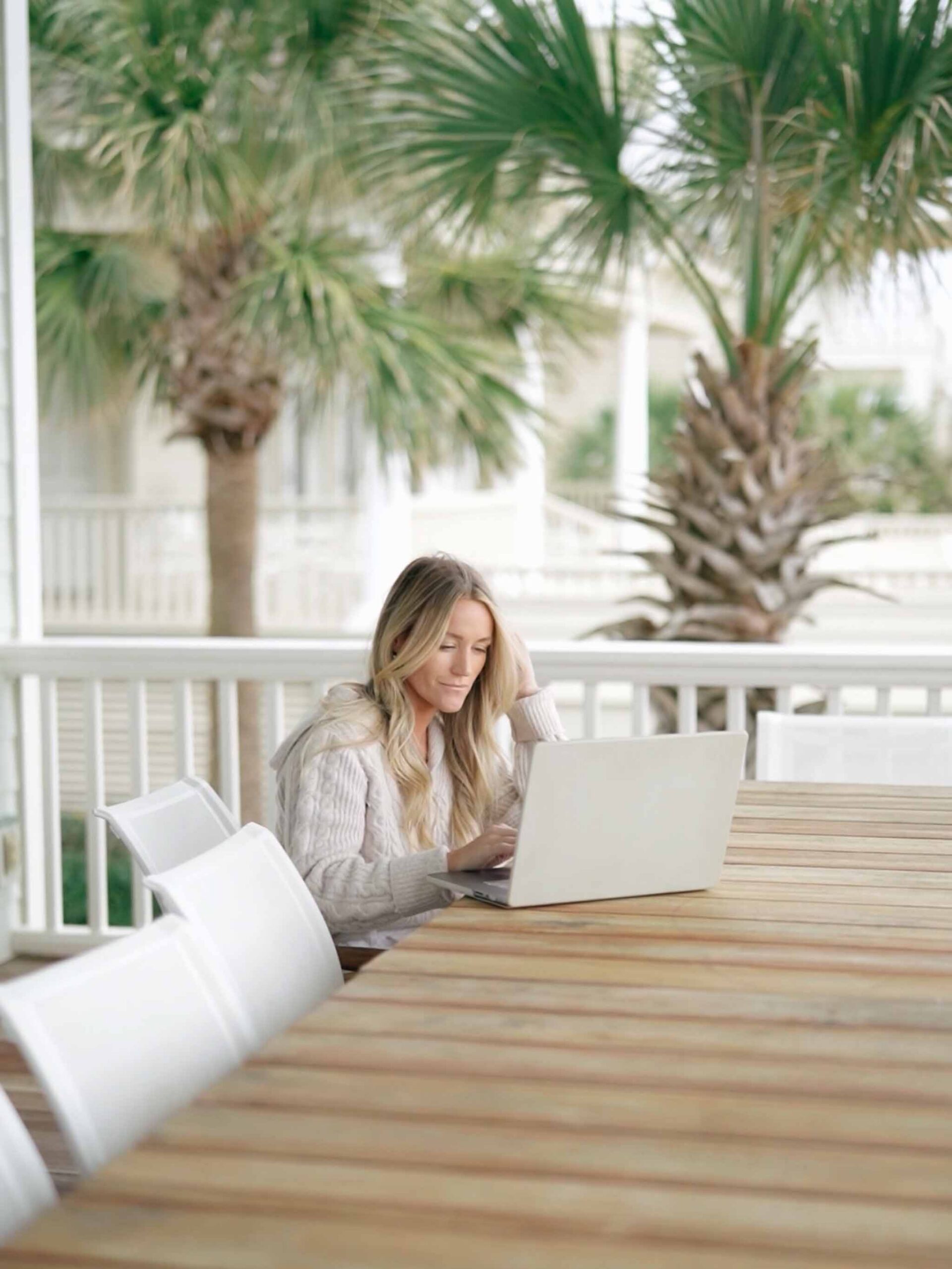 mandy ford seo expert for photographers works on an outdoor patio by the beach with her laptop